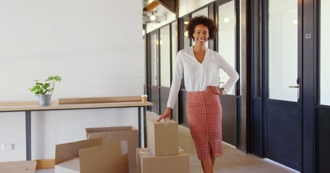 Confident african american businesswoman in modern office with moving boxes