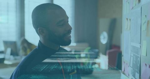 Bearded man studying sticky-note planning board with holographic data overlay
