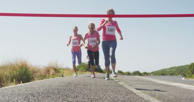 Elderly women crossing finish line in outdoor marathon, showcasing fitness and endurance. Great for articles on healthy aging, exercise for seniors, and marathon events. Emphasizes active lifestyle and motivation for older adults.