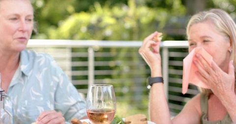 Senior friends laughing and dining outdoors
