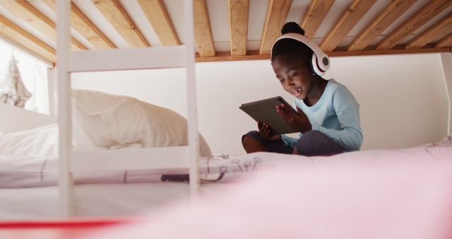 Young Girl Enjoying Tablet Under Bunk Bed While Wearing Headphones - Download Free Stock Images Pikwizard.com
