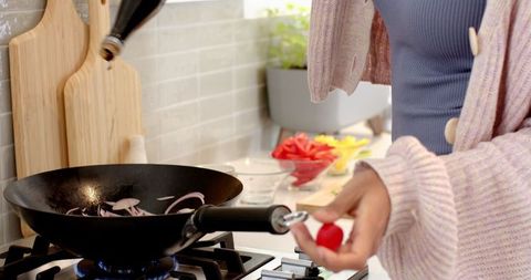 Woman in Cozy Sweater Cooking Vegetables in Modern Kitchen