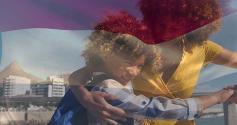 Mother and son embracing on sunny seaside promenade with translucent striped overlay