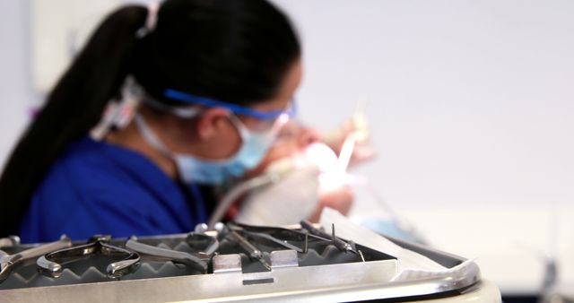 Health professional treating patient with focus on dental tools in foreground, suggesting theme of proper safety and meticulousness in dental practices. Useful for articles on dental care, healthcare advertisements, or educational purposes about oral hygiene.