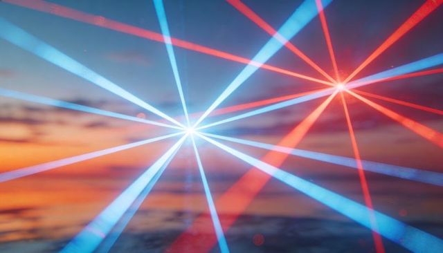Projecting twin starbursts over coastal sunset with red and blue laser beams reflecting on water
