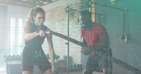 Woman training with battle ropes while coach guiding strength conditioning workout