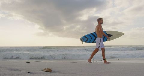 Young Man Walking with Surfboard on Beach at Sunset - Download Free Stock Images Pikwizard.com
