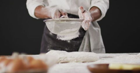 Chef sifting flour on rustic baking table