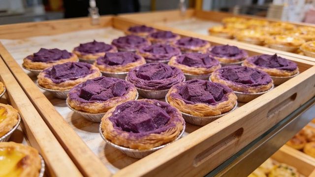 Displaying vibrant ube custard tarts with purple rosette filling on glass-topped bakery tray