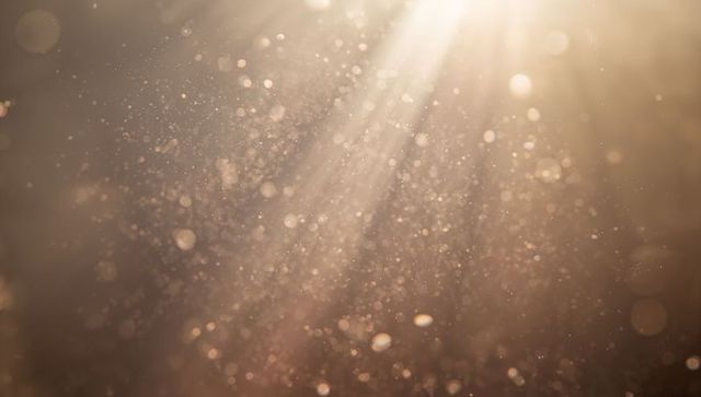 Warm golden sunbeams streaming through floating dust motes with soft bokeh glow