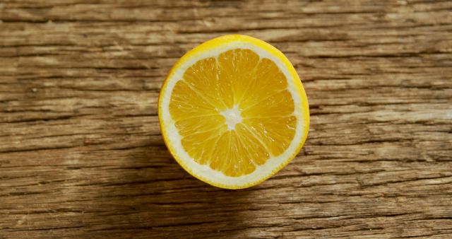 Halved fresh lemon displayed on rustic wooden background creating natural and organic aesthetic. Useful for advertisements, food blogs, healthy living articles, menus, and natural product marketing.