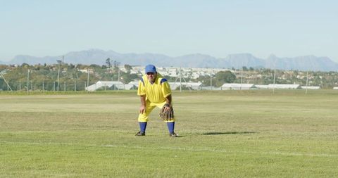 Mature Baseball Outfielder Standing Ready in Yellow Uniform with Glove on Grass Field