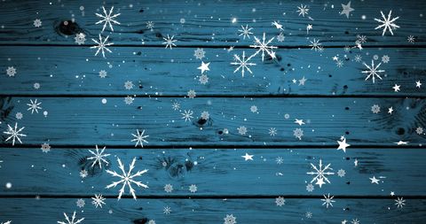 White snowflakes falling on blue wooden surface