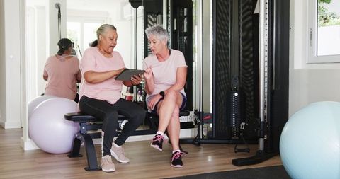 Senior couple discussing fitness goals via tablet in home gym