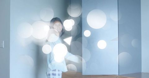 Standing woman in pastel loungewear with dreamy bokeh light in minimalist home corner