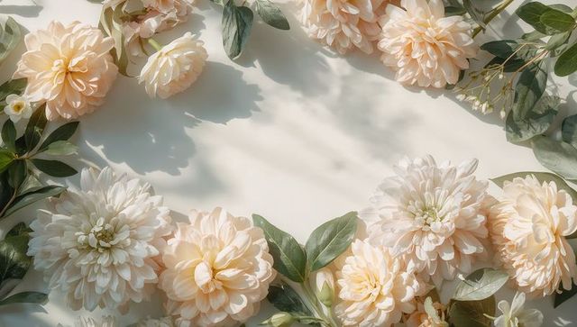 Peach cream dahlia floral frame with soft green foliage, pastel flat lay background