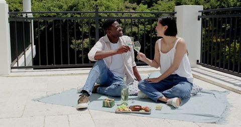 Couple enjoying romantic rooftop picnic with snacks and wine