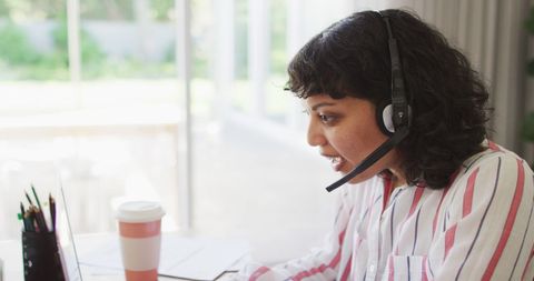 Focused Woman in Headset Working from Home on Laptop