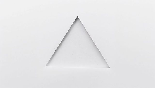 White paper triangle cutout creating minimalist geometric negative space beveled edges