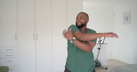 Man stretching in bright minimalist bedroom home gym, warming up for indoor cycling