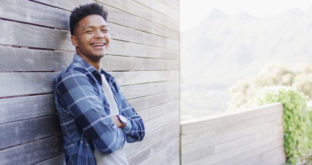 Young Man in Plaid Shirt Smiling Outdoors Against Wooden Wall - Download Free Stock Images Pikwizard.com