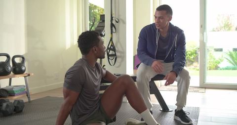 African american man receiving personal training in modern home gym coaching session