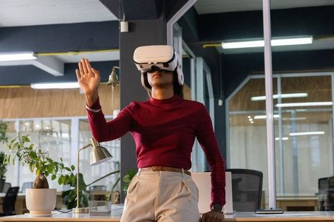 Indian woman wearing vr headset in modern coworking office, using gesture control