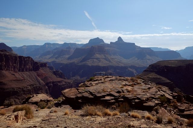 The rugged terrain of the Grand Canyon showcases steep cliffs and varying rock formations under a clear blue sky. Ideal for use in travel guides, nature documentaries, tourism advertisements, scenic calendars or educational materials about natural parks.
