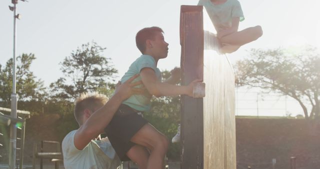 Children Climbing Over Wall with Adult Assistance in Outdoor Playground - Download Free Stock Images Pikwizard.com