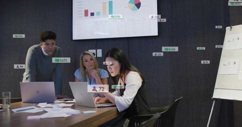 Team analyzing dashboard metrics on laptops presenting charts during collaborative boardroom session