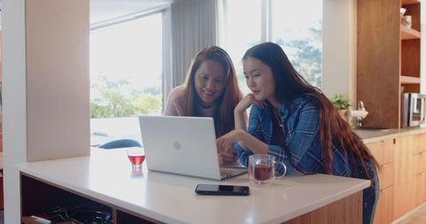 Mother and Daughter Bonding Over Laptop in Cozy Home Kitchen