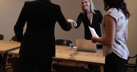 Businesswoman greeting colleagues in conference room