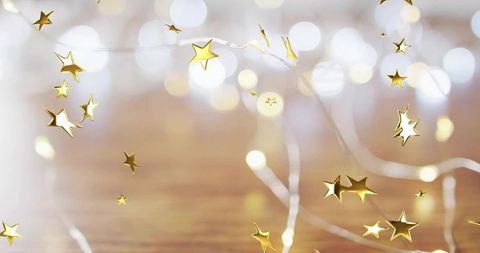 Glistening Gold Star Confetti Scattering on Warm Wooden Surface with Fairy Lights Bokeh