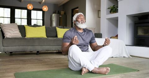 Senior african american man meditating at home, finding inner peace