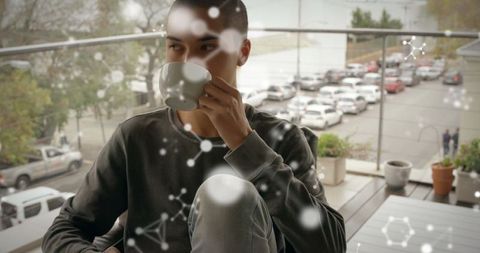 Relaxed Young Man Enjoying Morning Coffee on Urban Balcony