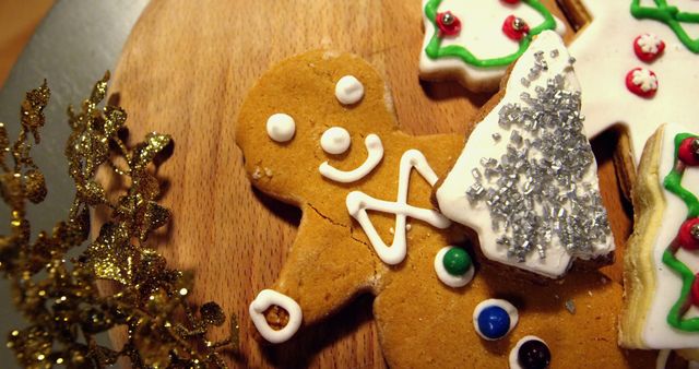 Decorated gingerbread cookies placed on wooden board with various icing designs. Featuring tree and star shapes alongside classic gingerbread man. Perfect for holiday advertising, greeting cards, recipes, baking blogs, festive social media posts.