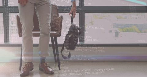 Businessman holding backpack with coding overlay in modern office