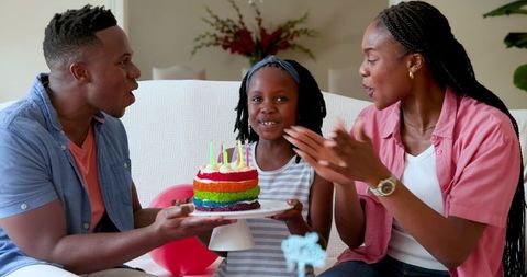 Happy Family Celebrating Daughter's Birthday with Rainbow Cake