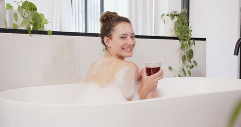 Woman Relaxing with Wine Glass in Luxurious Modern Bathtub