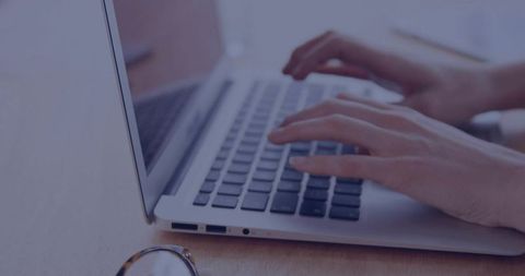 Woman typing on laptop keyboard closeup minimalist workspace with eyeglasses on desk