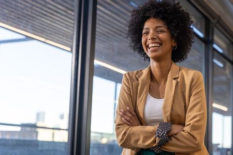Confident businesswoman smiling in modern office corridor
