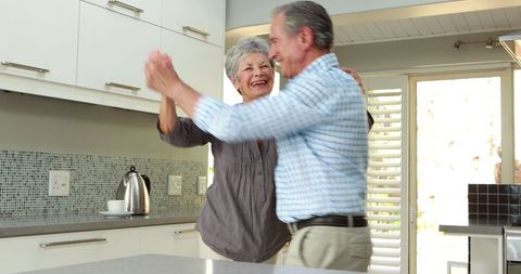 Senior Couple Joyfully Dancing at Home in Modern Kitchen