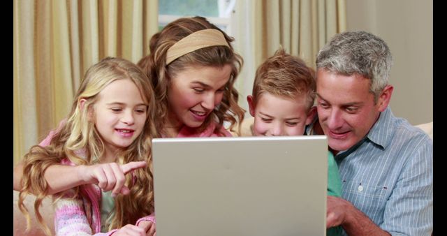 This captures a joyful family bonding over a laptop in a cozy living room atmosphere. Perfect for use in advertising family products, technology usage, internet safety, and family-oriented services.