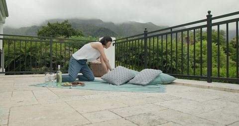 Woman arranging picnic setup on scenic terrace