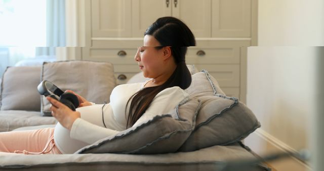 Pregnant Woman Relaxing on Couch Using Headphones for Baby Bonding - Download Free Stock Images Pikwizard.com