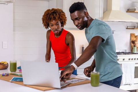African american couple planning home project on laptop in bright kitchen
