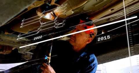 Mechanic inspecting undercarriage with augmented reality HUD timeline diagnostic overlay