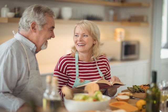 Senior couple reading recipe book while preparing meal in kitchen