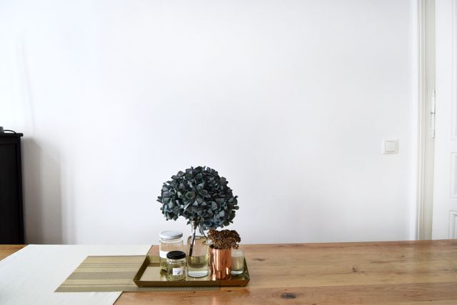 Minimalist wooden table decorated with green potted plant and candles, creating a clean and modern aesthetic. Suitable for articles on home decor trends, minimalist living, or modern interior design inspirations.