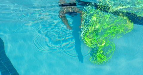 Man floating underwater with vibrant green pigment effect in pool